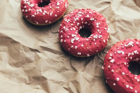 Fresh raspberry donuts on crumpled craft paper.