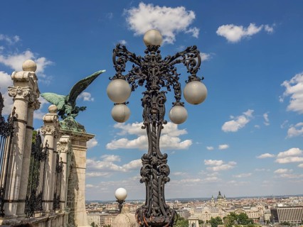 Artistic street lamp and green statue in front of a blue sky with clouds, budapest, danube, hungary