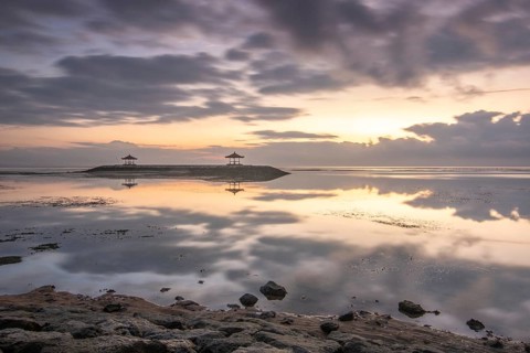 Beautiful seascape in the morning. Tropical sandy beach with breakwater and reflection of the sky