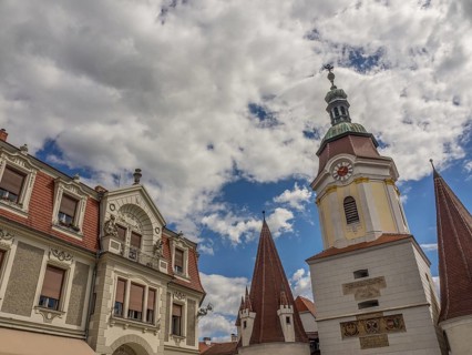 A town with historic buildings and a church tower under a partly cloudy sky, Dürnstein, Wachau,