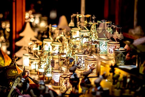 Many decorated Christmas lamps stand as decoration on a table in front of a blurred background