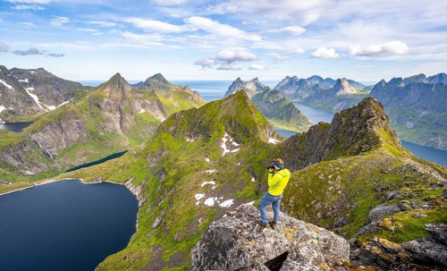 Mountaineer photographed at the summit of Munken, mountain landscape with steep rocky mountain