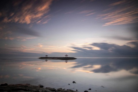 Beautiful seascape in the morning. Tropical sandy beach with breakwater and reflection of the sky
