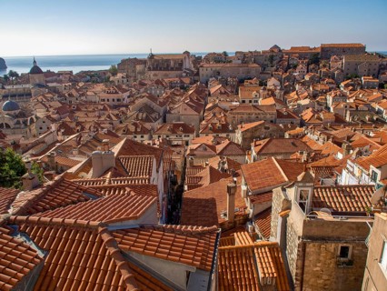 View of an urban roofscape with red tiled roofs and the sea in the background, dubrovnik,