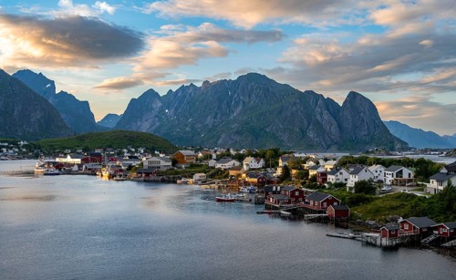 Village view of the fishing village Reine, Traditional red Rorbuer cabins, at sunset, rocky