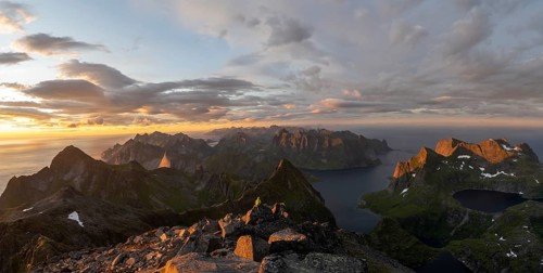 View over mountain peaks and sea, dramatic sunset, mountaineers at Hermannsdalstinden, with lakes