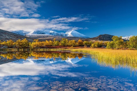 Reflection of the autumn landscape in Rondane National Park, snow-capped mountains, Doraldalen,