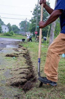 Detroit, Michigan, Volunteers clear weeds and grass in preparation for planting a roadside garden