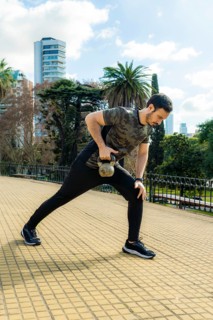 Young latin man doing exercises with kettlebell outdoor. Weightlifting workout. Sports, fitness