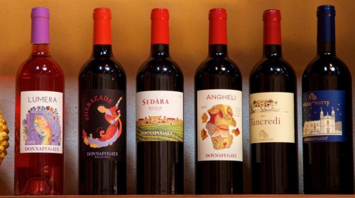 Various bottles of wine organised on a shelf, each with a unique label, Donna Fugata winery,