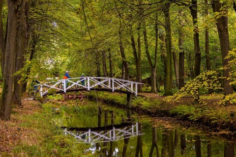 Cyclists pass a bridge in Hermsdorf Castle Park near Dresden