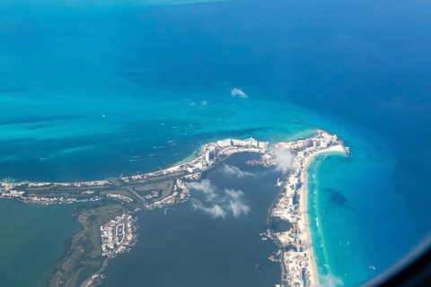 Aerial view through plane window of Caribbean coastline buildings in the hotel zone, Cancun,