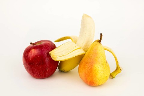 Half peeled banana with apple and pear, studio shot, white background, healthy food