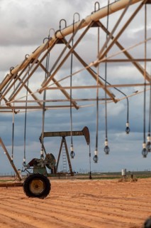 Plains, Texas, An oil well near irrigation equipment on farm land in the Permian Basin
