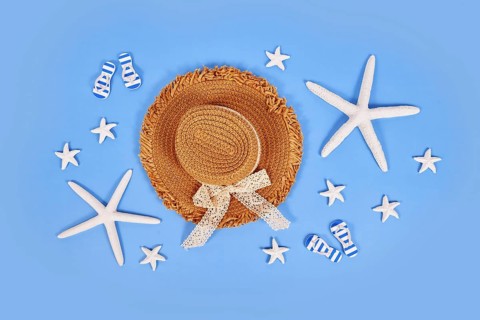 White starfish, summer straw hat and sandals on blue background