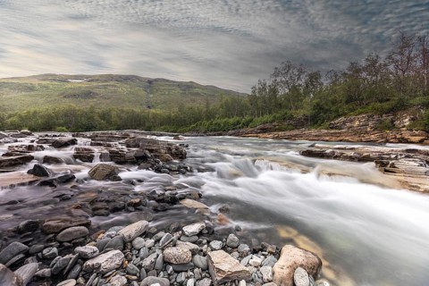 Abiskojakka, river in Abisko NP (northern Sweden) . Long exposure, clouds, rocks, forest
