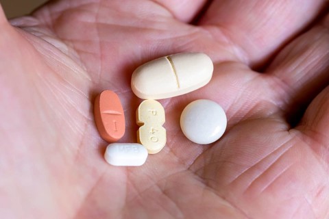 Hand holds various tablets, medicines