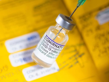 Symbolic image Corona vaccine Comirnaty in front of a vaccination certificate