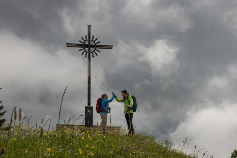 Young couple climbing, hiking, summit cross Brauneck, bad weather, fog. Brauneck near Lenggries,