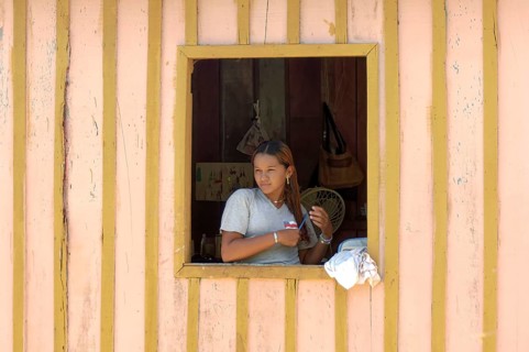Young woman of a caboclos tribe combing her hair at the window of her house along the Amazon River,