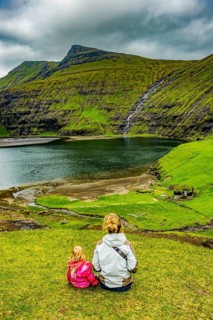 Woman with her child looking at the beautiful fjord of Saksun, Streymoy, Faroe islands, Denmark,
