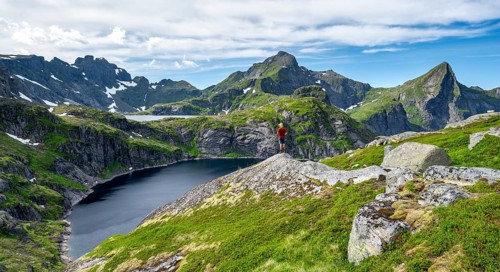 Mountaineer on a rock, mountain landscape with rocky pointed mountain peaks and lakes, with
