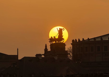 Sunset in Dresden. The sun's disc, particularly orange due to the Sahara dust, sets behind the