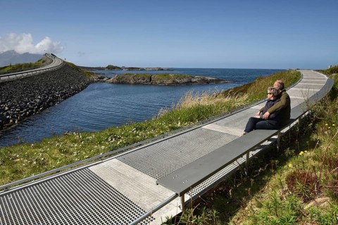 Couple sitting on a bench on the Atlantic Road in Norway