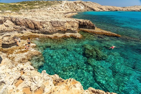 Tourists bathing in the crystal-clear turquoise waters of the Cape Greco peninsula, Agia Napa,