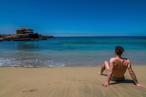 Young man with bathing-trunks, sitting on sandbeach. Tarrafal. Santiago. Cabo Verde. Africa