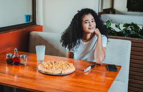 Beautiful afro hair girl in a pizzeria restaurant. Lifestyle of afro-haired girl sitting in a
