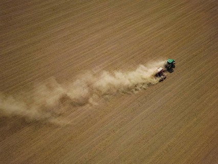 A tractor with a Horsch PRONTO DC 6 seed drill sowing in a dry field in late summer., Doma, Saxony,