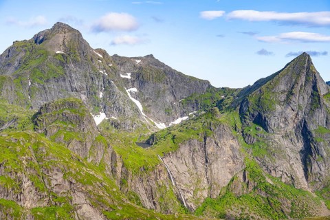 Mountain landscape with steep rocky peaks and waterfall, summit of Hermannsdalstinden, view from