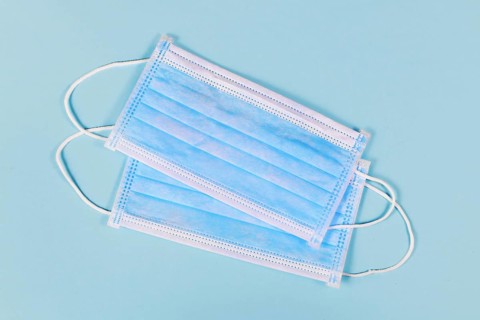 Two disposable medical face masks on blue background