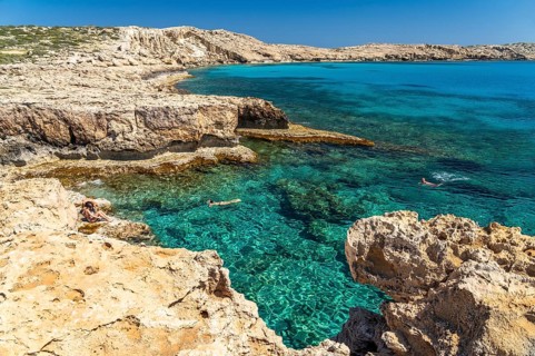 Tourists bathing in the crystal-clear turquoise waters of the Cape Greco peninsula, Agia Napa,