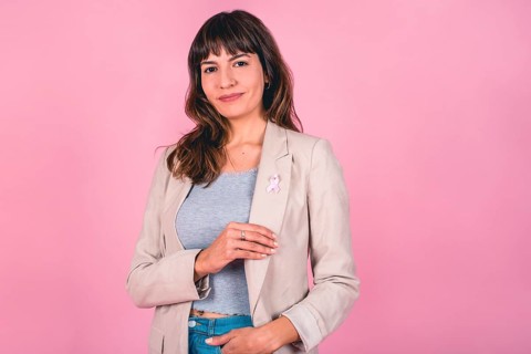 Beautiful woman wearing a pink breast cancer awareness ribbon while showing it
