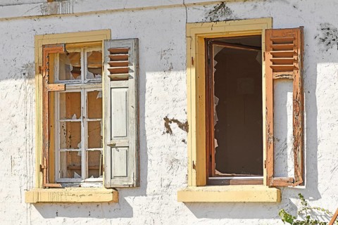 Two old damaged windows with shutters of old abandoned building