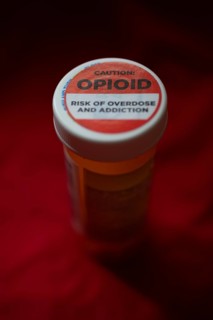 A label on a bottle of hydrocodone-acetamin opioid prescription pills warns against the danger of