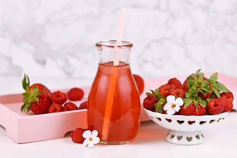 Strawberry fruit lemonade in jar surrounded by berries
