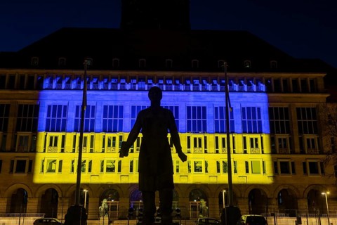 Dresden City Hall illuminated in the Ukrainian national colours, in the foreground the monument to