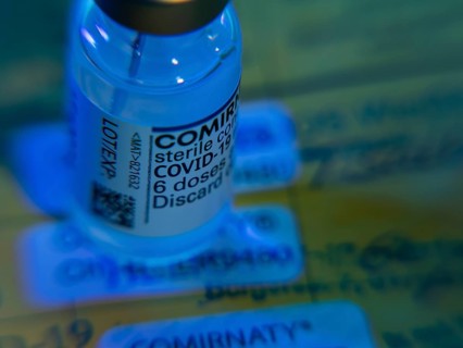 Symbolic image Corona vaccine Comirnaty in front of a vaccination card
