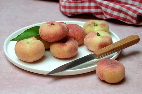 Peach, flat peaches in peel with knife