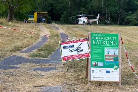 Signs for soil protection liming at a cordoned-off helicopter landing site, forest edge,