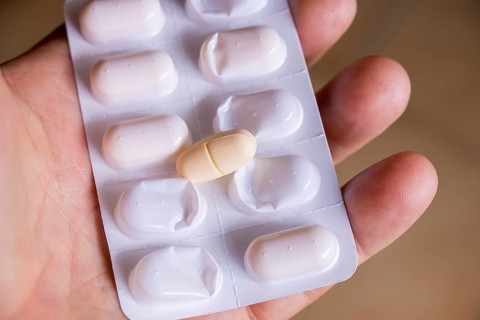 Hand holding a blister pack with a tablet