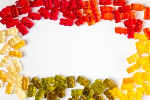 Frame made of gummy bears in assorted colours, from above, white background, copying space in the