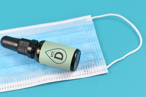 Medical face mask and bottle with vitamine drops on blue background