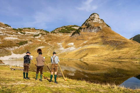 Three men play the alphorn at Lake Augstsee on Mount Loser. The Austrian alphorn trio Klangholz.