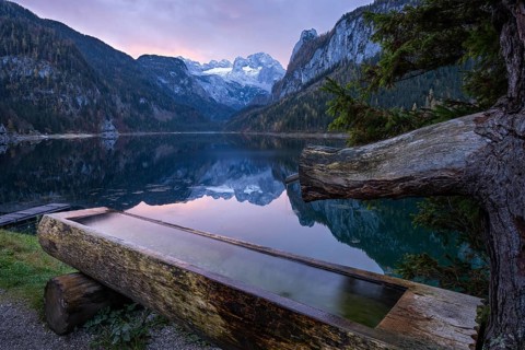 The Vordere Gosausee lake in autumn with a view of the Dachstein mountain range. A water trough in
