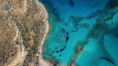 Drone shot, aerial view of a rocky coast with turquoise water and a small jetty, Gramvoussa,