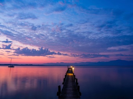 Sailing boat and jetty on Lake Chiemsee at dawn, behind the Chiemgau Alps, Chiemgau, Upper Bavaria,